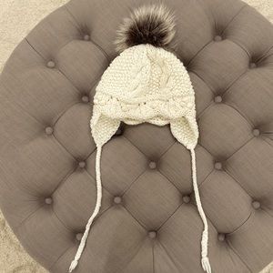 Ivory knit beanie with ear flap and gray raccoon pom